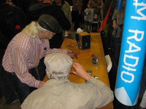 A visitor (striped shirt and black hat) tries some of the hands-on microwave physics demonstrations made by Walt